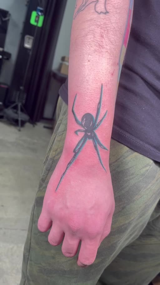 Black spider tattoo on the wrist and hand